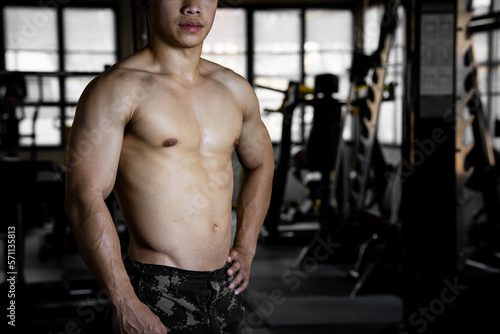 Sexy body of muscular young Asian man in gym. Concept of health care, exercise fitness, Strong muscle mass, body enhancement, fat reduction for men's health supplement product presentation.