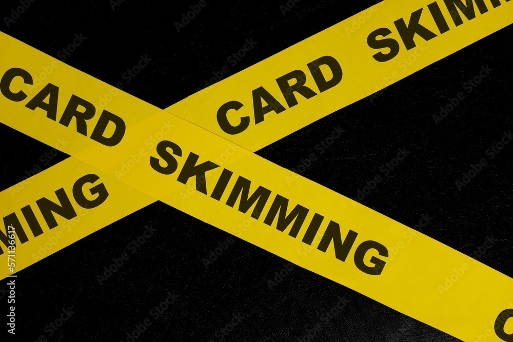 Card skimming cybercrime and theft alert, caution and warning concept. Yellow barricade tape with word in dark black background.