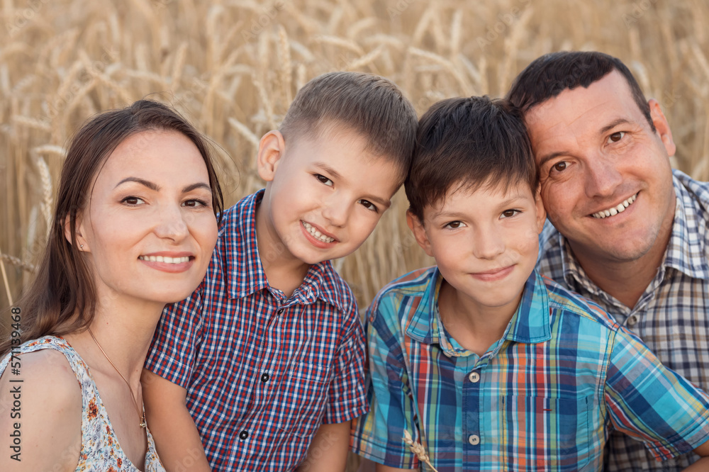 Happy family demonstrates toothy smile and enjoys summer holidays against ripe wheat field. Parents and little sons grimacing show excited expression, closeup Happy family demonstrates toothy smile and enjoys summer holidays against ripe wheat field. Parents and little sons grimacing show excited expression, closeup