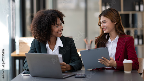 African American businesswoman and Asian businesswoman working together as a team to get their project done.