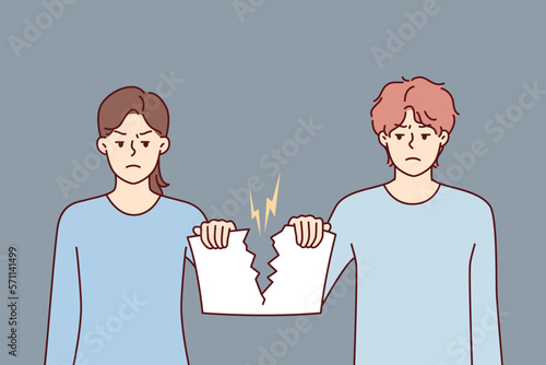 Angry man and woman holding sheet tearing joint paper after quarrel or family disagreement. Guy and girl with hatred in their eyes tear document confirming marriage