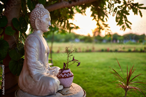 Buddha sculpture outdoors at yoga school. An Indian village, lots of greenery around.