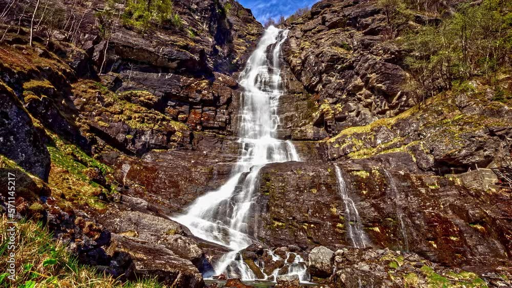 Timelapse of a large waterfall on a rocky cliff and in the background we can see the sky with clouds Timelapse of a large waterfall on a rocky cliff and in the background we can see the sky with clouds