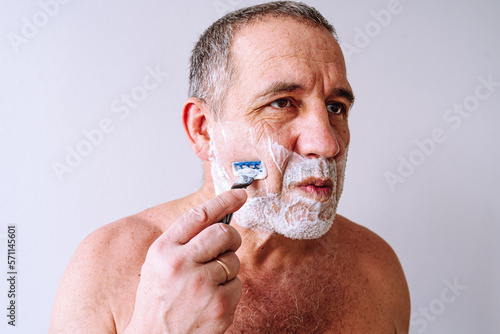 man shaves facial hair with disposable razor with safety blade