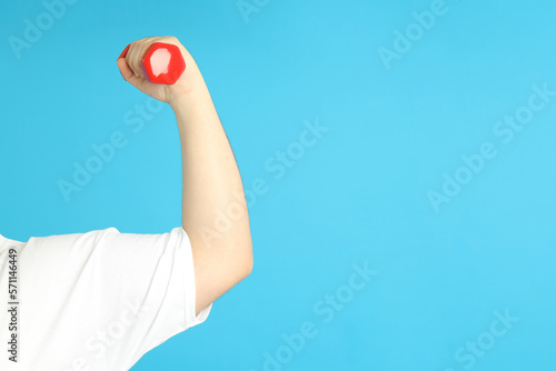 Concept of weight loss, male hand with dumbbell on blue background