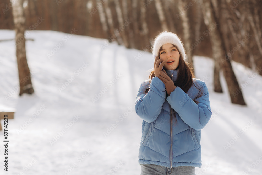 Happy woman calls on mobile phone while walking in winter park Happy woman calls on mobile phone while walking in winter park
