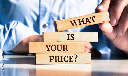 Close up on businessman holding a wooden block with "What is Your Price?" message