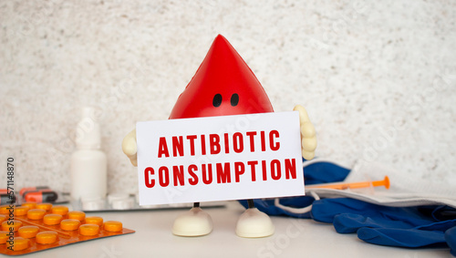 A toy drop of blood holds a white paper card with the inscription ANTIBIOTIC CONSUMPTION.