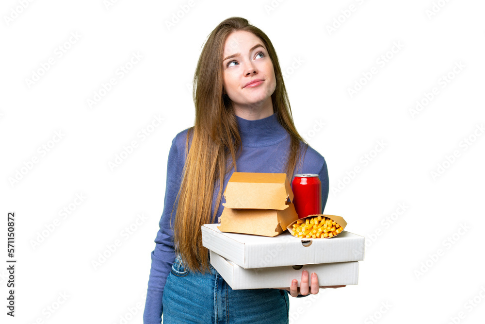 Young pretty woman holding pizzas and burgers over isolated chroma key background and looking up Young pretty woman holding pizzas and burgers over isolated chroma key background and looking up