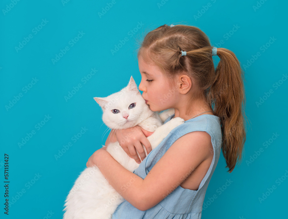 Little girl kissing her white cat over blue background. Little girl kissing her white cat over blue background.