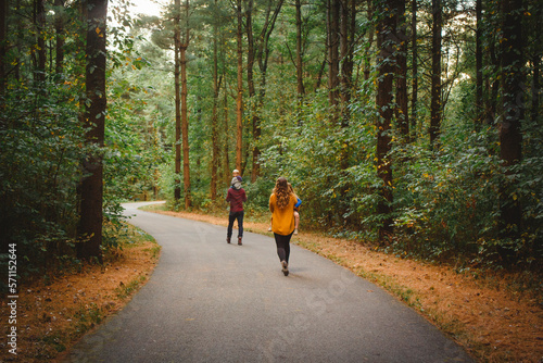 Rear-view of a family walking through a winding forest path in Autumn