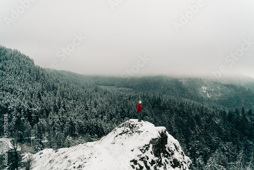 A young woman stands on the top of a snowy point in the Columbia Gorge photo