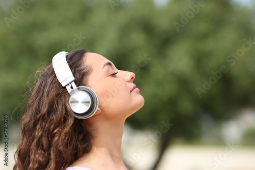 Relaxed woman with headphones meditating in a park