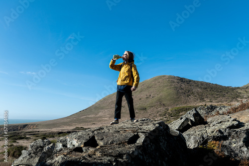 Tween standing outside on rocks drinking from water bottle confidently photo