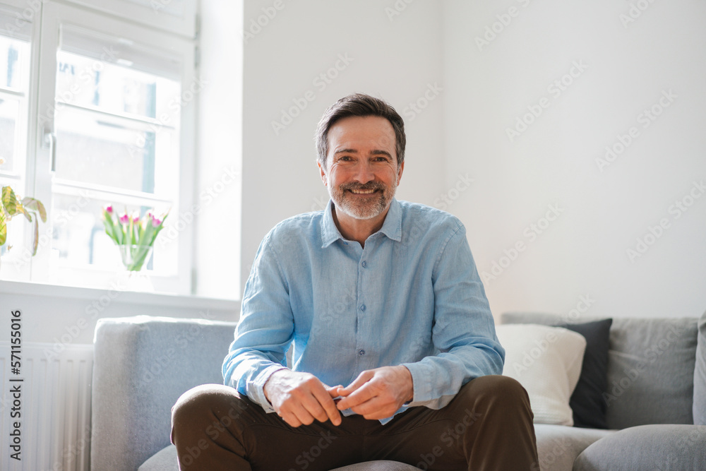 Smiling mature man sitting on sofa at home Smiling mature man sitting on sofa at home