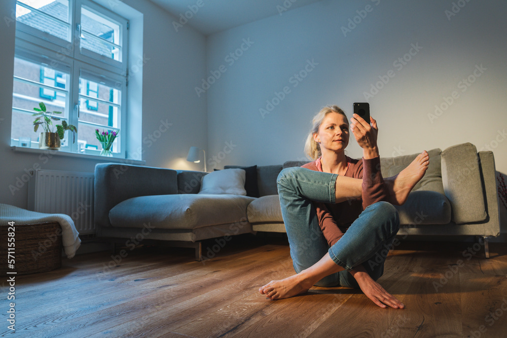 Mature woman using smart phone and practicing yoga at home Mature woman using smart phone and practicing yoga at home