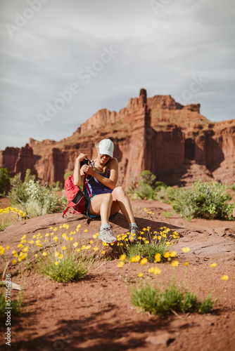 hiker takes off backpack to rest under red sandstone towers photo