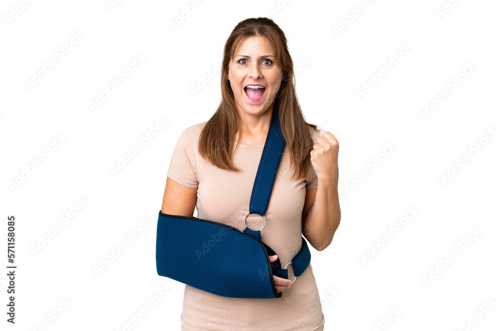 Middle age with broken arm and wearing a sling over isolated background celebrating a victory in winner position Middle age with broken arm and wearing a sling over isolated background celebrating a victory in winner position