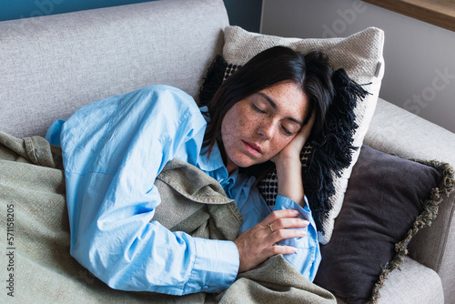 Young woman with eyes closed resting on sofa at home
