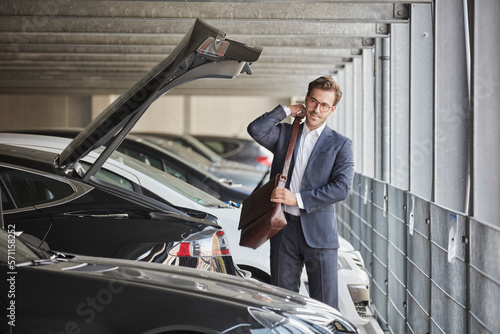 Businessman standing with shoulder bag in parking garage