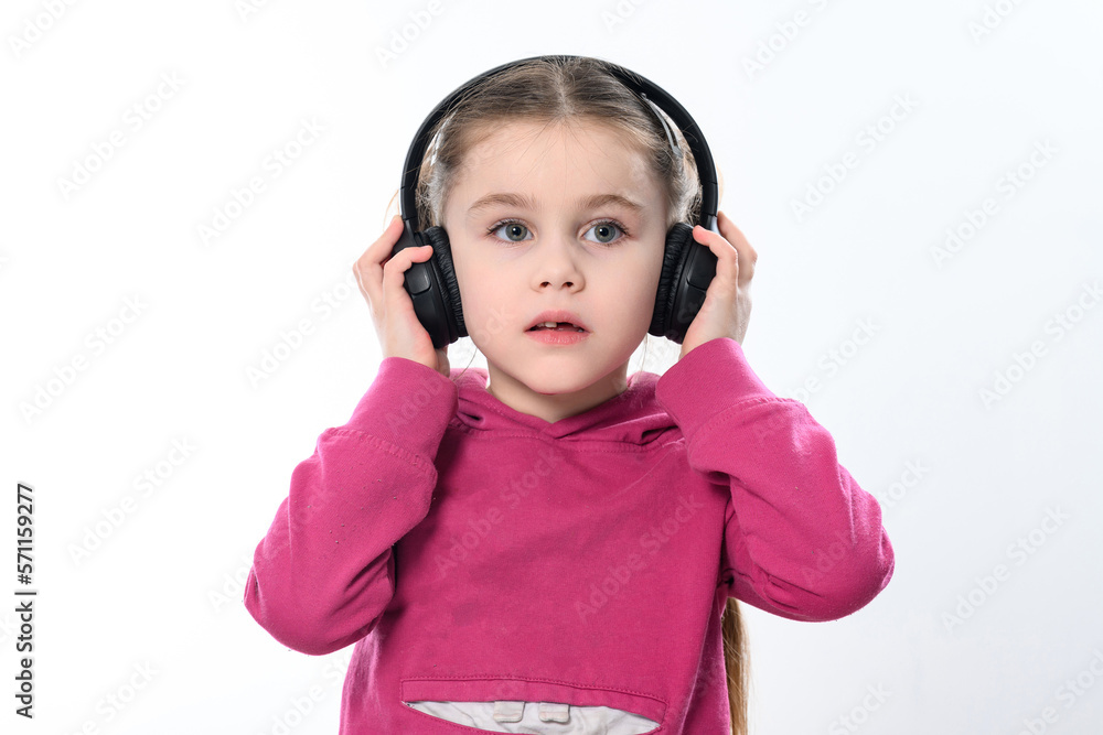 A child with headphones on a white background, a cheerful and beautiful girl with headphones. A child with headphones on a white background, a cheerful and beautiful girl with headphones.