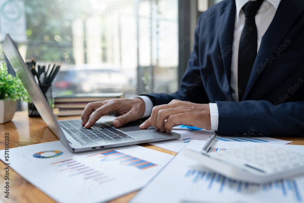 Young Asian businessman using a laptop computer to record financial information on Corporate income tax within the office. Young Asian businessman using a laptop computer to record financial information on Corporate income tax within the office.