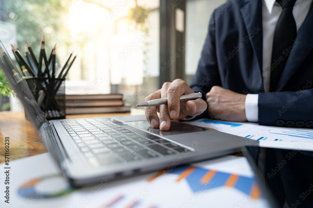 Young Asian businessman using a laptop computer to record financial information on Corporate income tax within the office. Young Asian businessman using a laptop computer to record financial information on Corporate income tax within the office.
