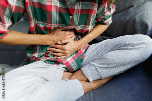 Woman touching stomach sitting on sofa at home