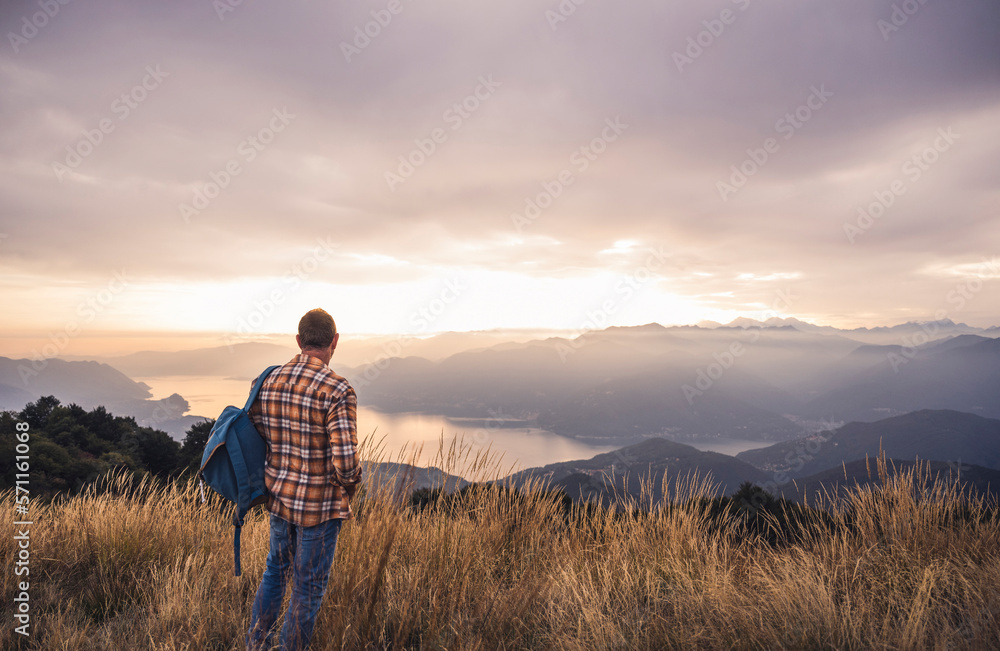 Mature man with backpack standing on mountain at sunset Mature man with backpack standing on mountain at sunset