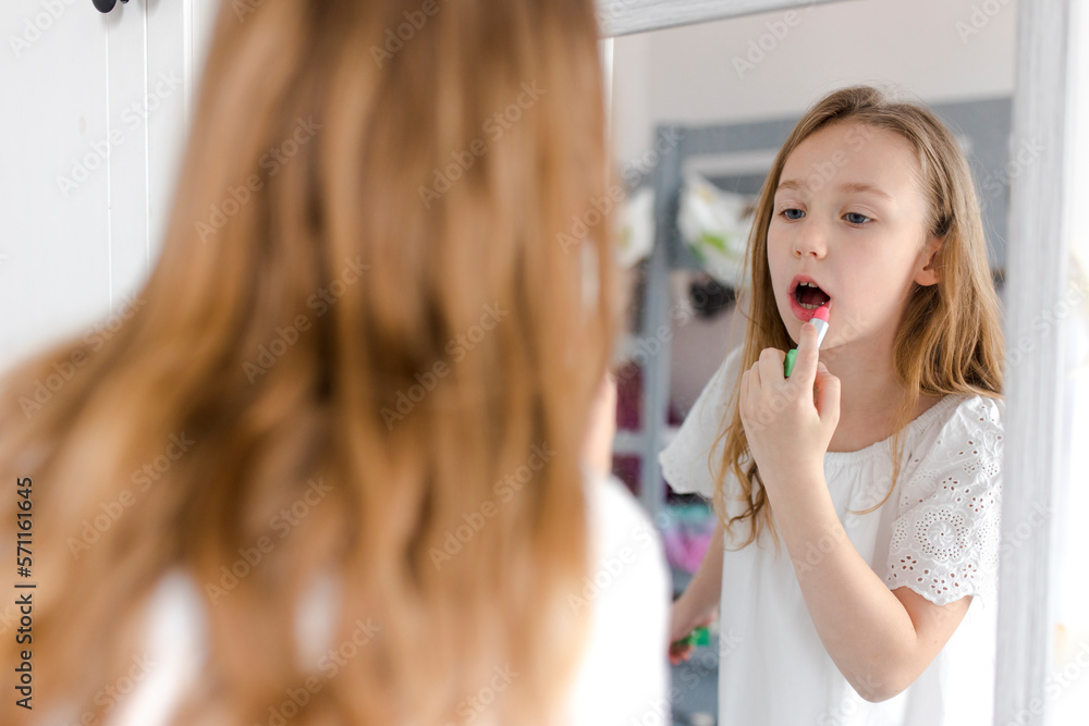 Girl looking in mirror and applying lipstick at home