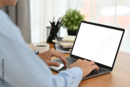 Side view of young businessman hands typing on laptop computer working on commercial at workstation