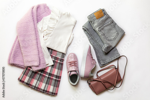 8 year old Girl clothes set, white blouse, grey geans and plaid skirt, pink sneakers, small  bag on white background. photo