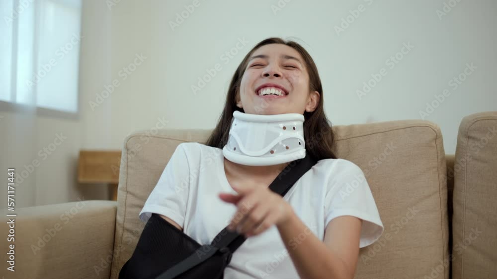 Happy woman recovery watching tv using remote from accident fracture broken bone injury with leg splints in cast, neck splints collar, sling support arm. Social security and health insurance. Happy woman recovery watching tv using remote from accident fracture broken bone injury with leg splints in cast, neck splints collar, sling support arm. Social security and health insurance.