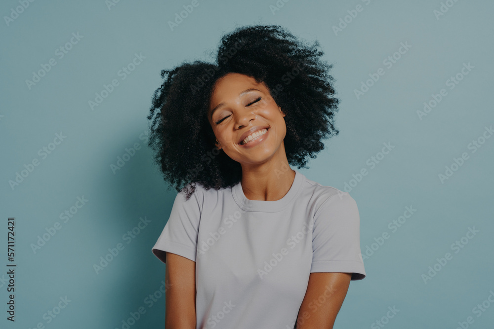 Portrait of cheerful young woman with afro hairstyle isolated over pastel blue studio background Portrait of cheerful young woman with afro hairstyle isolated over pastel blue studio background