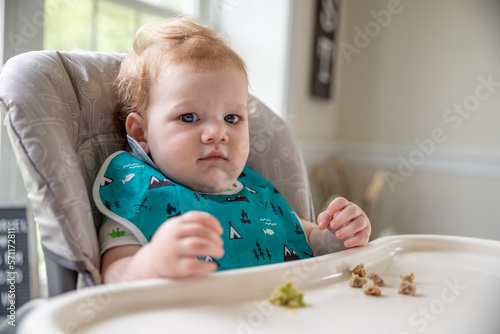 Baby boy sitting in high chair waiting for food.