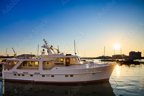 White yacht in commercial port, motor boats in Black sea at sunset.