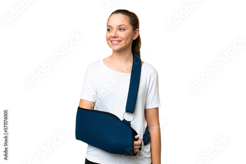 Young blonde woman with broken arm and wearing a sling over isolated chroma key background looking side