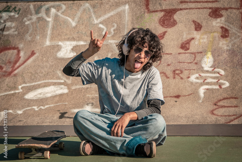 Obraz na plátně teenager with skateboard and headphones making rebel gesture