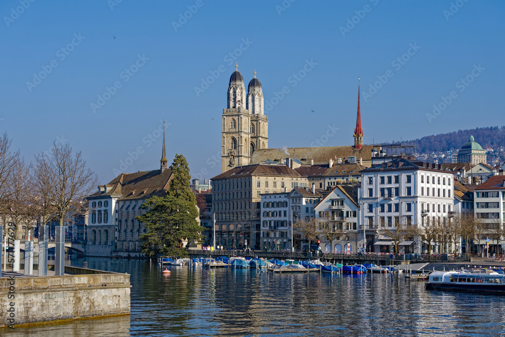 Scenic view of Limmat River with Minster Bridge and the skyline of the old town of City of Zürich with church Great Minster on a sunny winter day. Photo taken February 9th, 2023, Zurich, Switzerland.