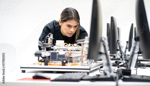Computer science development engineer working on robotic arm connection and control at electronic futuristic technology center. Modern woman training in industry 4.0 automated engineering workshop