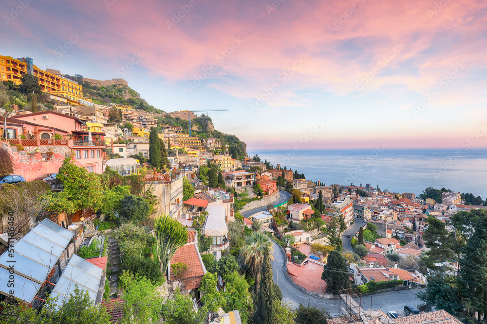 Stunning Aquamarine blue waters of sea and fantastic cityscape of Taormina during sunset.