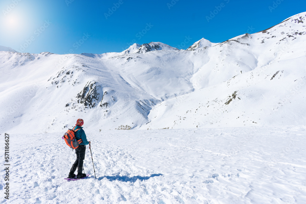 woman in mountain gear contemplates the snowy mountain scenery