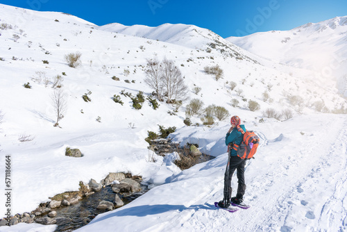 woman in mountain gear looking the snowy river mountain