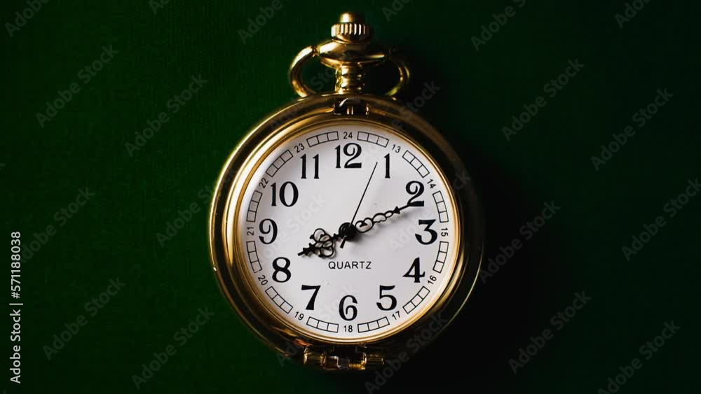 A gold quartz crystal pocket watch lying on dark green fabric. Time lapse of a clock. A gold quartz crystal pocket watch lying on dark green fabric. Time lapse of a clock.