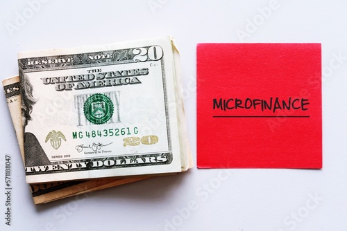 Cash Dollars money and red note with text written MICRO FINANCE , A banking service provided to unemployed or low-income individuals , groups who no access to traditional financial loan photo