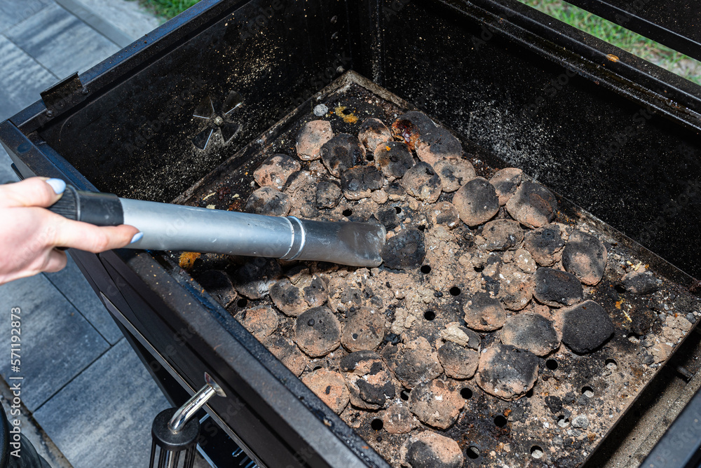 Cleaning a dirty grill while standing on the terrace and emptying the ashes. Cleaning a dirty grill while standing on the terrace and emptying the ashes.