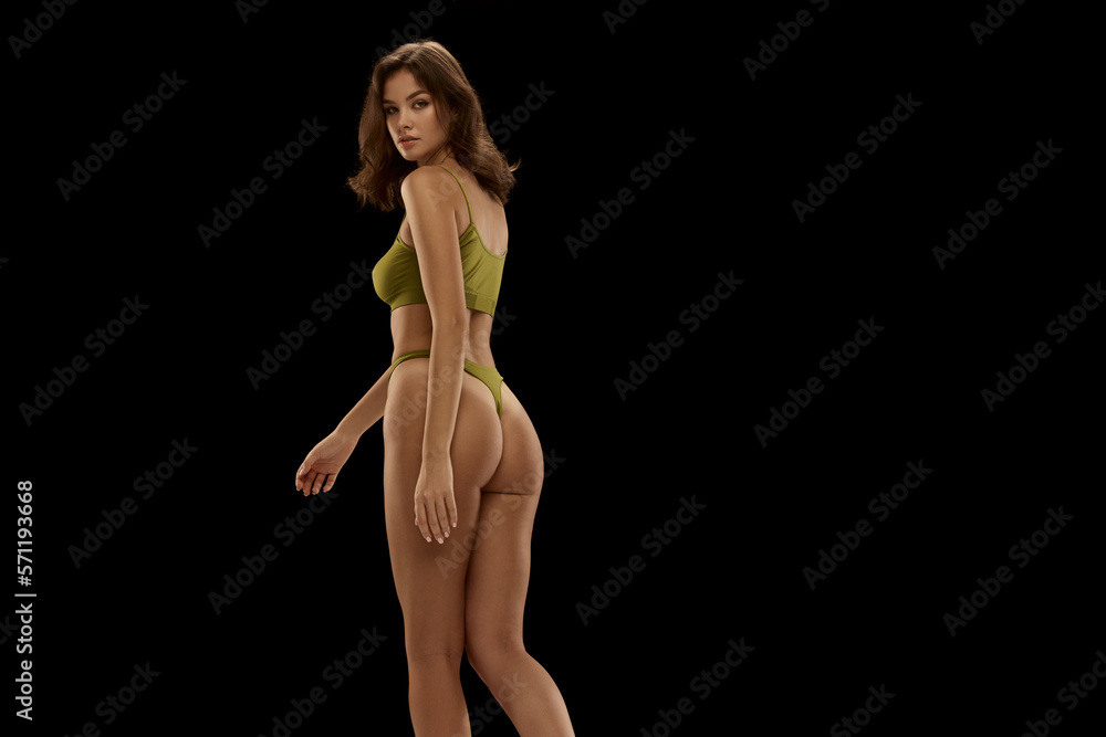 Portrait of young attractive woman posing in olive color lingerie isolated over black background. Concept of beauty, body and skin care, health, plastic surgery, cosmetics, ad Portrait of young attractive woman posing in olive color lingerie isolated over black background. Concept of beauty, body and skin care, health, plastic surgery, cosmetics, ad