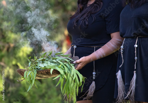 Australian Aboriginal smoking ceremony, woman‚Äôs hands are holding burning eucalyptus branches, the ritual rite at the community event, symbol of indigenous culture and traditions