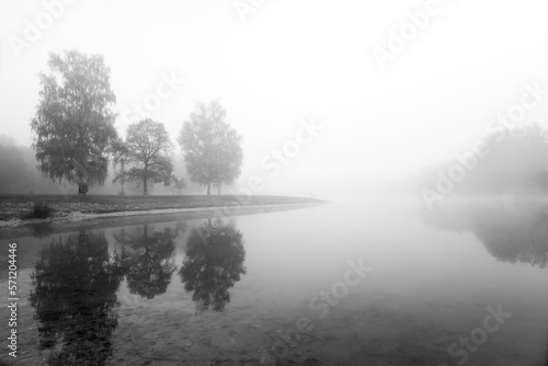 Germeringer See near Germering in Upper Bavaria. Landscape at the lake in the fog. Black and white shot. Foggy morning in nature. 