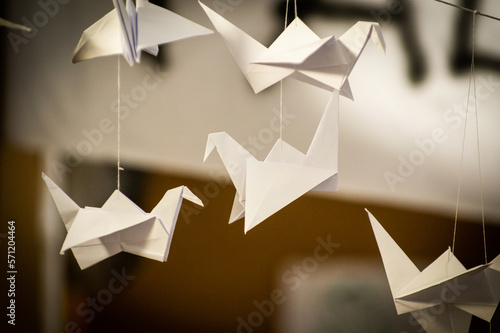 Japanese folded Origami cranes hanging on with strings. Hundreds handmade paper birds isolated with copy space. 1000 thousand crane sculpture topic. Symbol of peace, faith, health, wishes, hope photo
